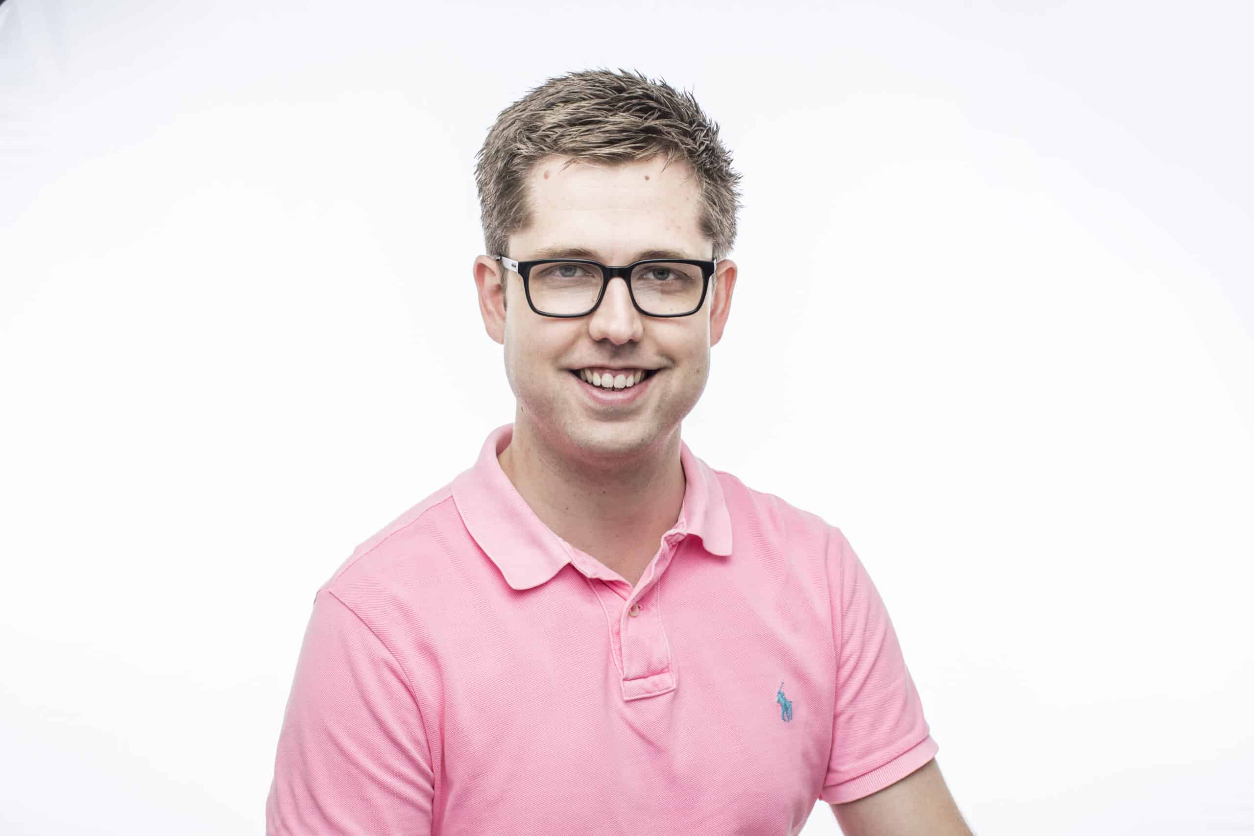 A man wearing glasses and a pink polo shirt.