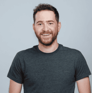 A bearded man wearing a gray t - shirt.