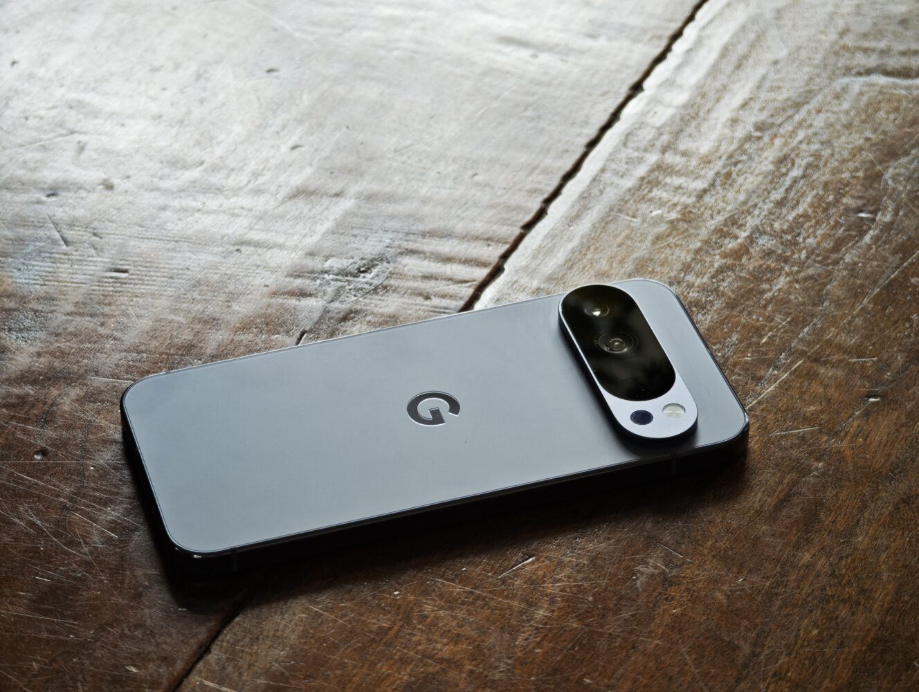 A Google Pixel smartphone with a dual rear camera is placed face down on a wooden surface.
