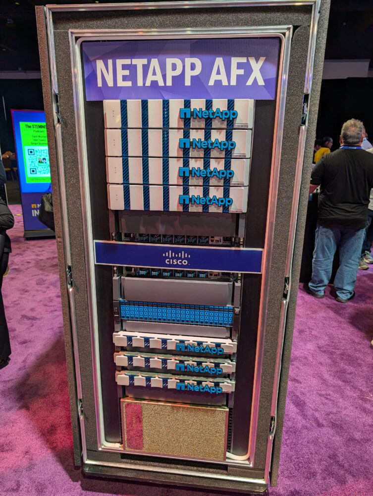NetApp AFX_2 A server rack labeled "NETAPP AFX," featuring multiple NetApp AFX drives and a Cisco component, is displayed on a purple carpet at an event.