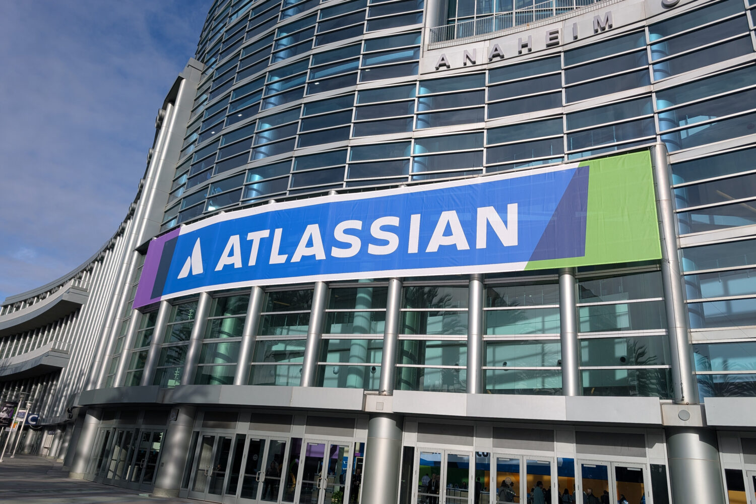 A large building with a glass facade displays a prominent "Atlassian" banner above the entrance, hinting at innovation within—perhaps even powered by the Atlassian Teamwork Graph.